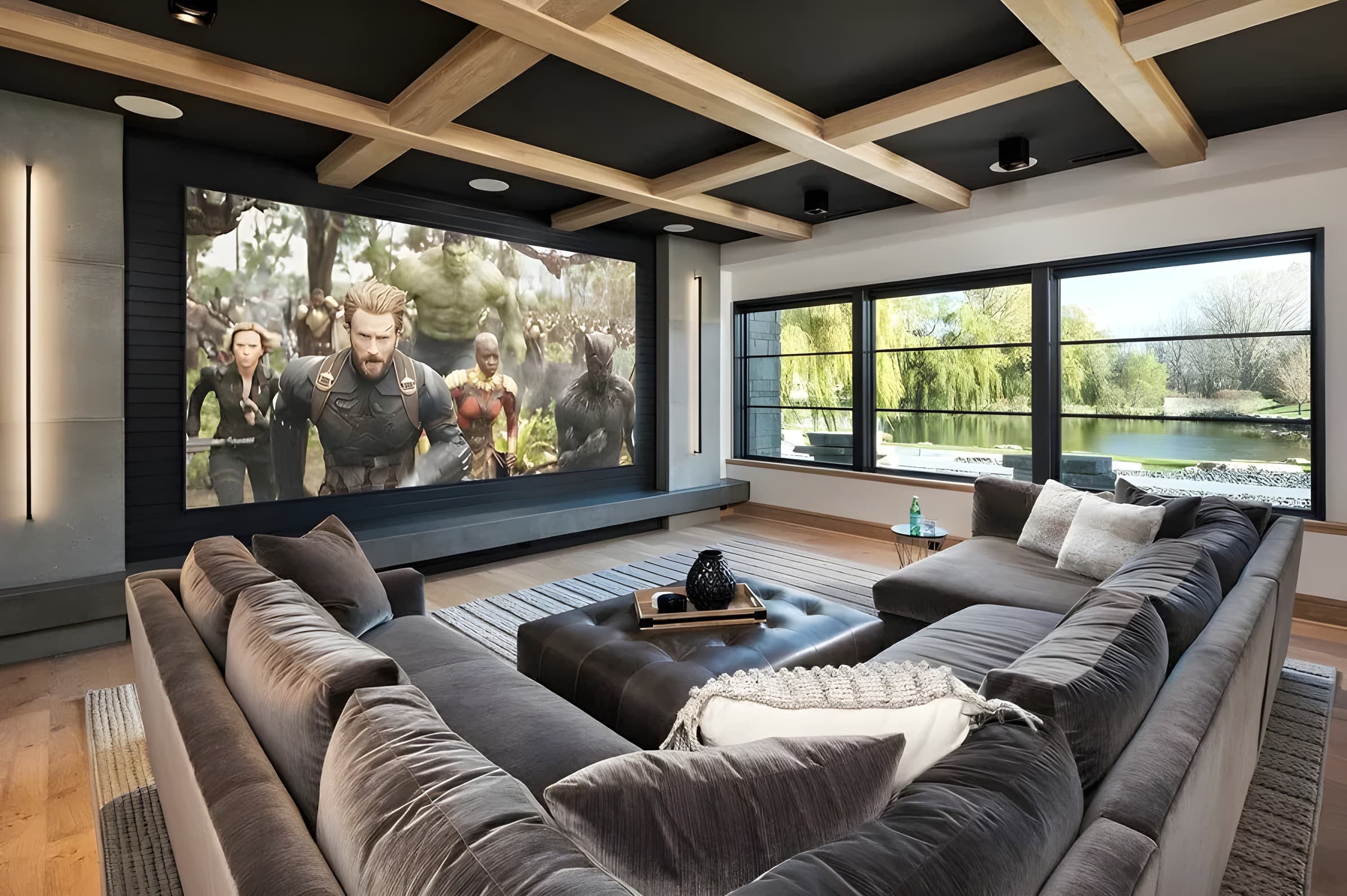 A family room theater with a coffered ceiling, a deep sectional and a large screen beside garden windows